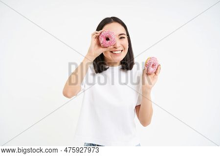 Cute Smiling Korean Woman, Looks Through Doughnut Holes, Eating Tasty Donnuts, Isolated Over White B