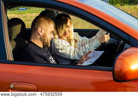 On A Sunny Day, A Driving Instructor Appreciates The Results Of A Womans Driving. A Woman Sits Behin