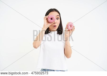 Cute Smiling Korean Woman, Looks Through Doughnut Holes, Eating Tasty Donnuts, Isolated Over White B
