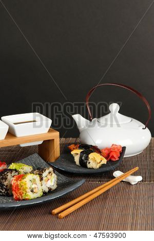 Velsmagende Maki sushi - Roll på grønne blade på bordet på grå baggrund