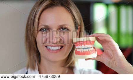 Close-up Of Smiling Woman Stomatologist Showing Perfect Tooth Model. Teeth Orthodontic Dental Model 
