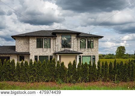 Real Estate Exterior Front House On A Sunny Day. Big Custom Made House With Back Yard In The Suburbs