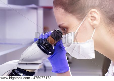 A Young Woman Doctor (laboratory Assistant) Conducts A Study Of A Blood Sample On A Microscope.  Clo