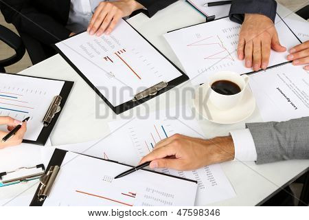 businesspartners hands during discussion of papers close up