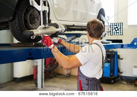Young serviceman checking wheel alignment  in a car workshop 