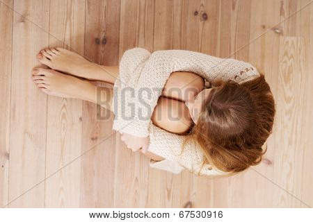 Beautiful caucasian woman is sitting on the floor. Looks as she were hiding from sth.