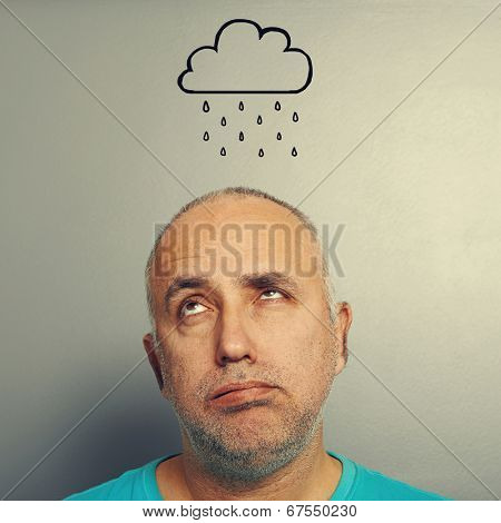 portrait of stressed senior man with drawing storm cloud over grey background