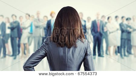Powerful businesswoman standing with back with business team at background