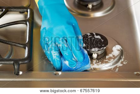 Hand Wearing Rubber Glove While Cleaning Stove Top Range With Soapy Sponge