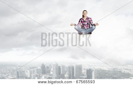 Young woman sitting on chair and meditating