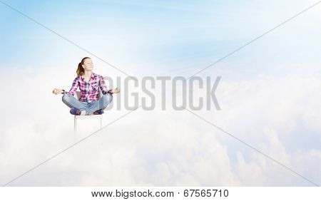 Young woman sitting on chair and meditating