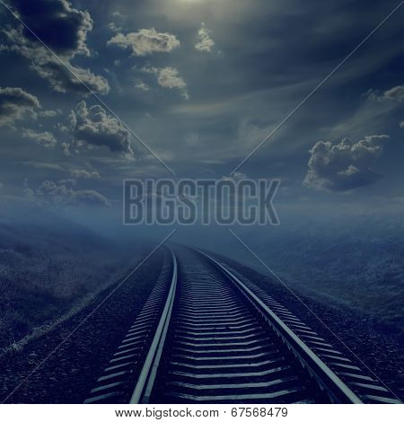 railroad in night to horizon in fog. moonlight in cloudy sky
