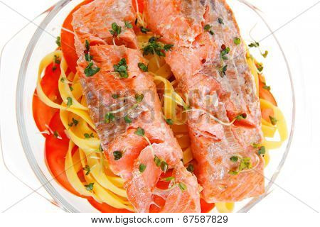 fresh fried natural pink salmon on italian traditional tagliatelle backed with tomato and vegetables isolated over white background