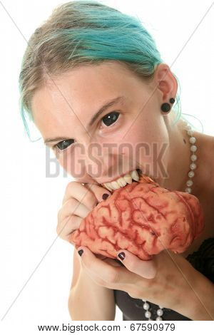 A young woman dressed as a Vampire - Zombie complete with black contacts and Vampire Fangs enjoys eating the brain of her latest victim. Isolated on white with room for your text 
