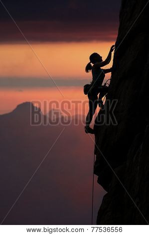 Slim female climber and sunset