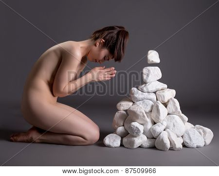Meditation. Nude girl moving stones mentally