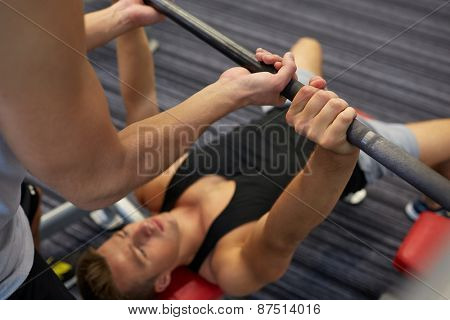 sport, fitness, teamwork, weightlifting and people concept - young man and personal trainer with barbell flexing muscles in gym