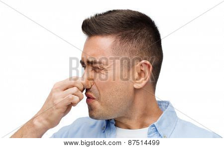 emotions, gesture and people concept - man wrying of unpleasant smell and closing his nose