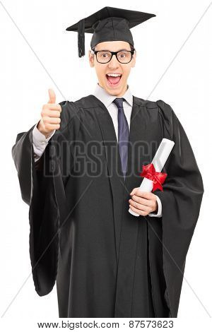 Vertical shot of an overjoyed graduate student in a graduation gown, holding a diploma and giving a thumb up isolated on white background