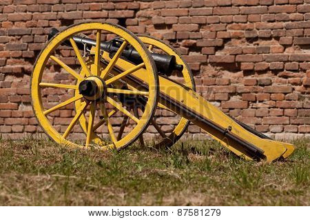 Old cannon in front of a brick wall