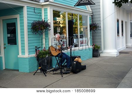 HARBOR SPRINGS, MICHIGAN / UNITED STATES - AUGUST 4, 2016: Musicians perform in front of Mary Ann Archer's fine jewelry store at the Street Musique event in downtown Harbor Springs.