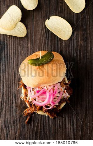 Slow cooked pulled pork with BBQ sauce pickled onions coleslaw and cheese served in a hamburger bun with dill pickle and chips as sides. It's a messy sandwich but so delicious!