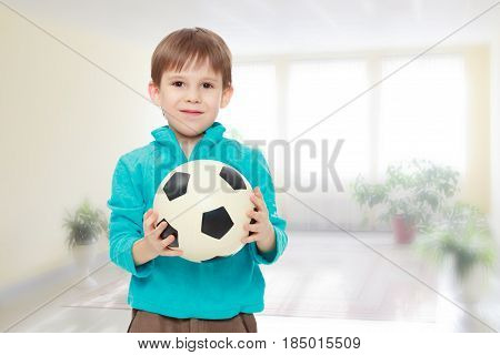 Little boy in brown pants and blue shirt playing with a soccer ball.Close-up.During a lesson in school.