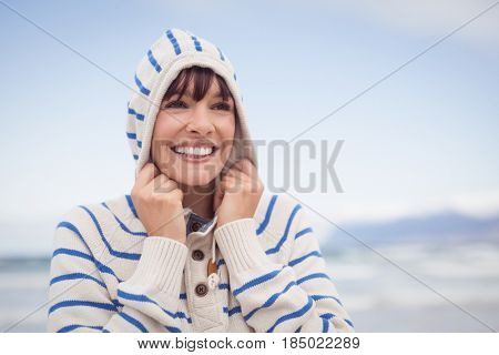 Thoughtful woman wearing hooded sweater at beach during winter