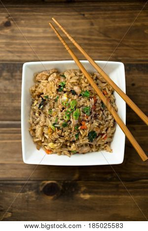 Chicken fried rice. Basil chicken fried rice with chopsticks on a wooden background viewed from above. This thai inspired meal is perfect for a quick lunch or served as side dish.