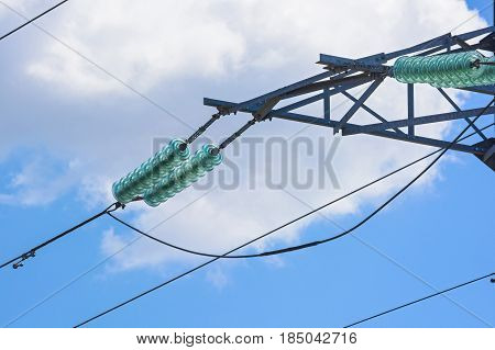 Close up high voltage wire on electricity pylon against blue sky