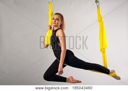 Yoga fly practice. Young happy woman working out in yellow hammock. Body balance and antigravity training. Wellness and body care concept.