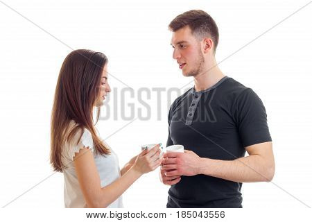 beautiful young guy with a girl look at each other and carrying cups of tea isolated on white background
