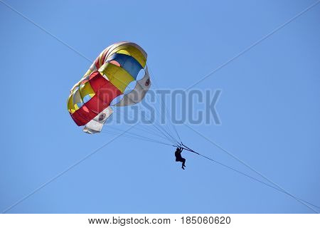 Bright parachute against the blue sky .