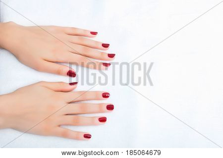 Female hands with manicure and red lacquer on a white table in the beauty salon