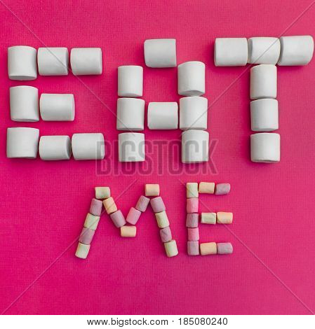 Marshmallows Background with colorful marshmallows Multicolored marshmallows are lying out in the form of the inscription Eat me Pink background