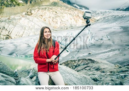 Young Woman Hiking in the Swiss Alps, Taking a Selfie. This is a generic, low-cost camera and not the 'famous original' brand.