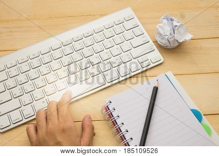Top View. Hand Of Woman Typing Spacebar Key, Garbage Paper Put On Beside Keyboard And Empty Notebook