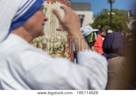 Fatima Portugal - May 13 2014: Blurred silhouette of a nun with the figure of the Virgin Mary on the background at the Sanctuary of Fatima during the celebrations of the apparition of the Virgin Mary in Fatima Portugal.