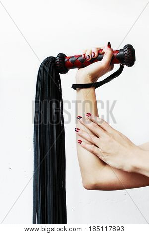 The handle of a red and black lash in a female hand on a white background