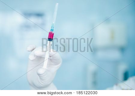 nurse holds a syringe with a universal vaccine against the zik virus, epidemic of ebola, poultry and swine flu, malaria, hepatitis. The concept of saving from disease.