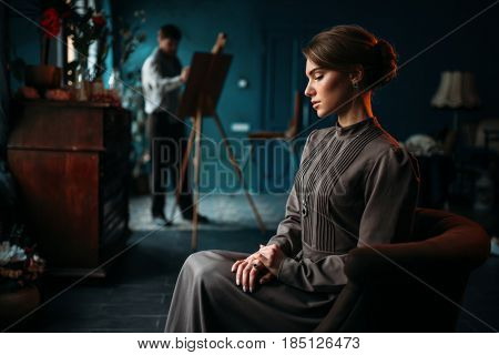 Female poseur, painter against easel on background