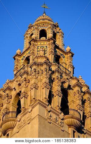 A well lit and ornate cathedral tower stands against a briliant blue sky. Balboa Park