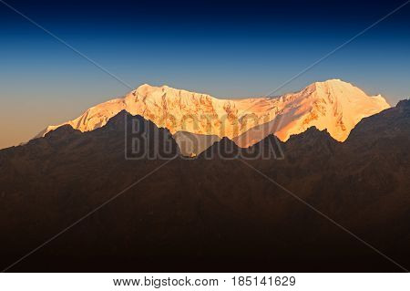 Beautiful first light from sunrise on Mount Kanchenjugha Himalayan mountain range Sikkim India. Orange tint on the mountains at dawn