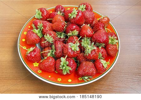 Photo of ripe juicy strawberry in a red plate