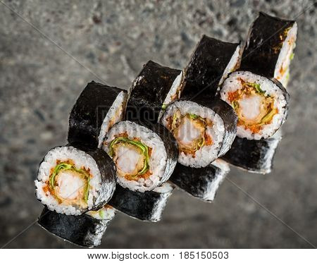 Sushi roll with shrimp, lettuce and tobiko over cocnrete background