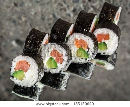 Sushi roll with salmon, cream cheese and avocado over cocnrete background