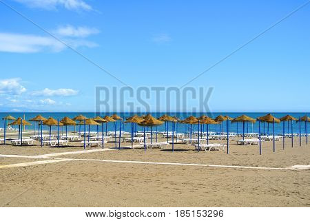 Summer Holiday View Of A Mediterranean Beach Prepared For A Tourist Season, A Sandy Beach By The Blu