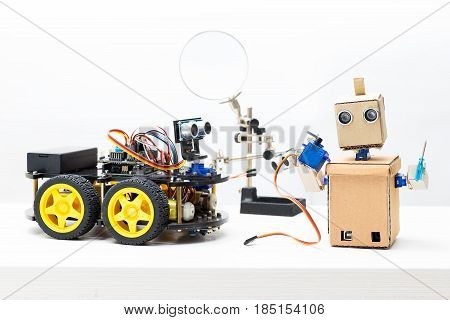 Two robots stand on the table. Robot holds servo and prop
