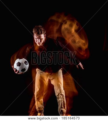 A portrait of a fan with ball on gray studio background. Freestile concept. Stroboscope shooting technique