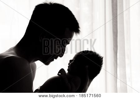Father day bonding concept with newborn baby nursing. Father is playing and talking with newborn baby beside window. Single Dad concept